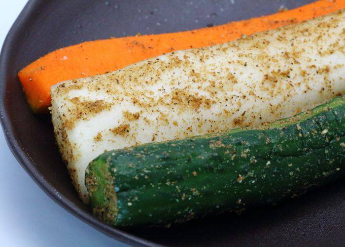 Pickled carrots, daikon radish and cucumbers on a black plate.